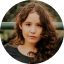 Close-up portrait of a woman with long wavy hair sharing a positive customer testimonial about price comparison
